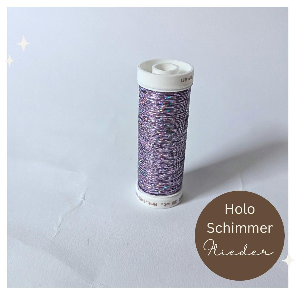 Eine Spule mit schimmerndem, violettem Metallic-Garn mit einem weißen Etikett mit der Aufschrift "Idk. Art. 145-6843".